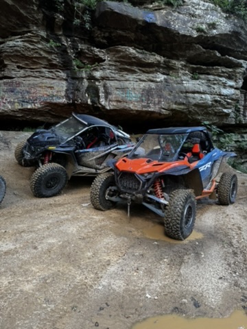 Two RZRs parked under a rock overhang